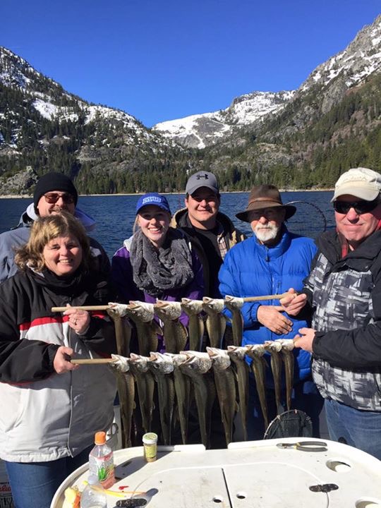 A group of people standing around holding fish.