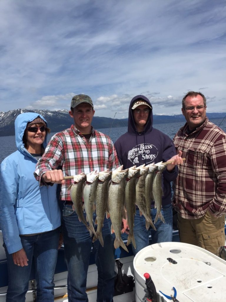 A group of people holding fish on top of a boat.