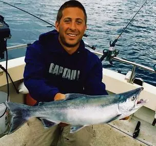 A man holding a fish while sitting in a boat.