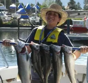 A woman holding five fish on a boat.