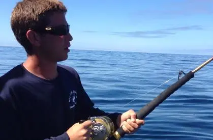 A man holding a fishing rod in the ocean.