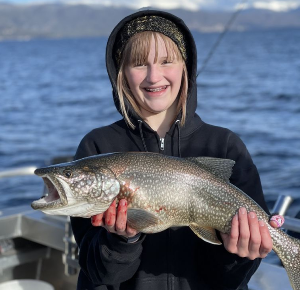 A young girl holding a fish on the boat.