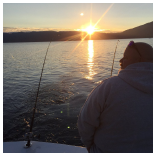 A person on a boat fishing at sunset.