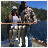 A man and woman holding fish on the boat.