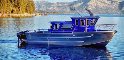 A blue boat is in the water near some trees.